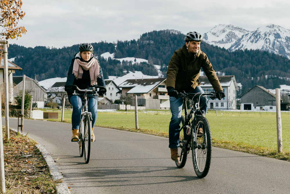 Mann und Frau fahren vor Bergkulisse mit dem Fahrrad.